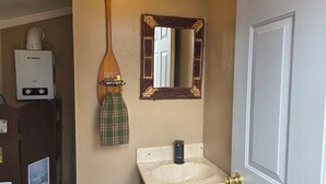 Un bagno con un lavandino bianco, uno specchio e un portasciugamani con un asciugamano a quadri.