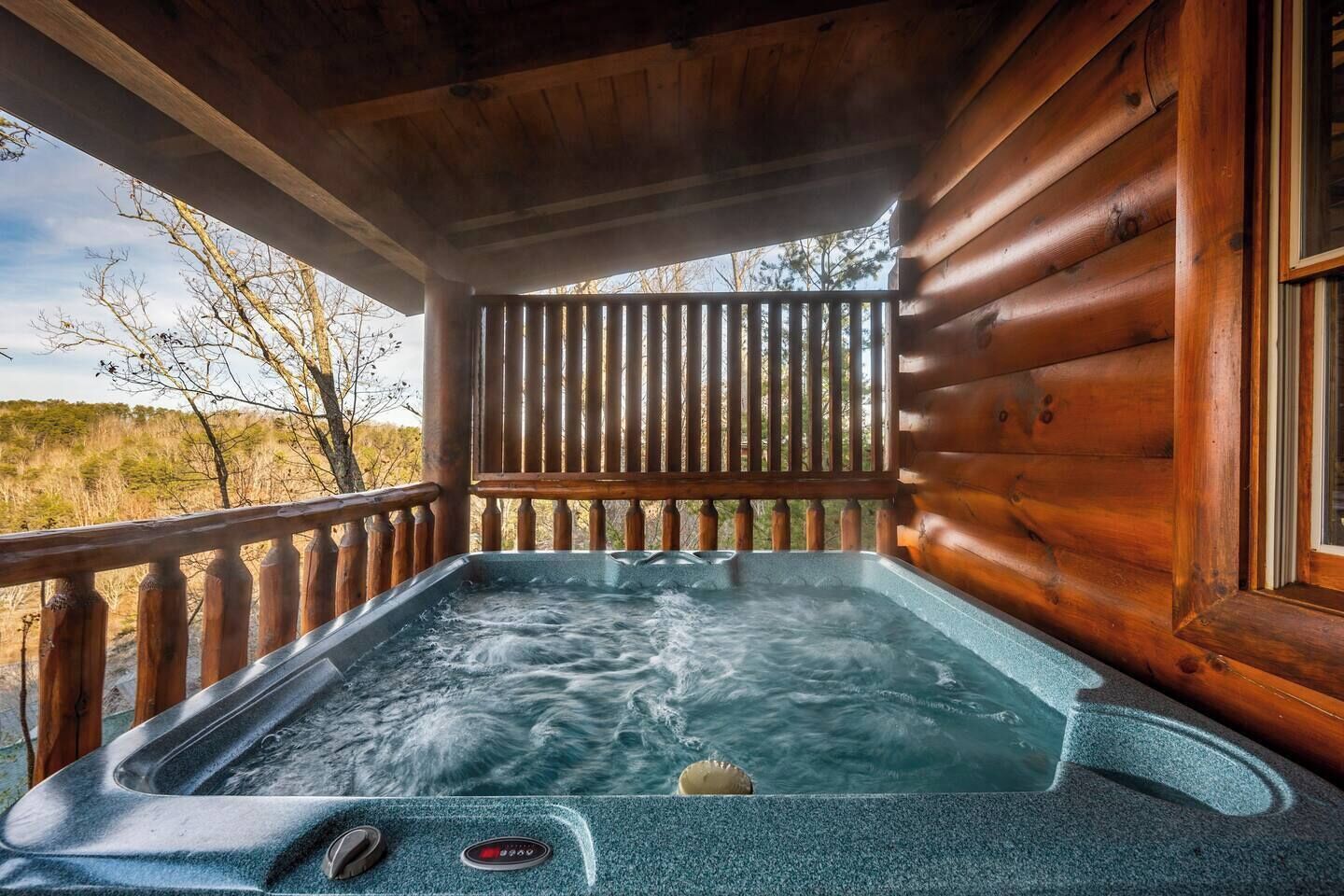 Uma cabana de madeira com uma banheira de hidromassagem na varanda.