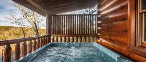 Uma cabana de madeira com uma banheira de hidromassagem na varanda.