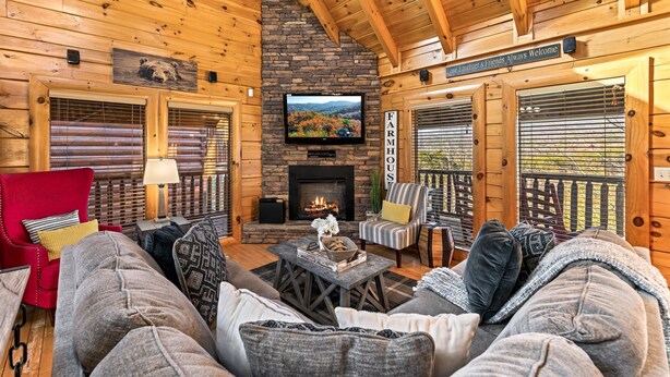 A cozy cabin interior with a stone fireplace, wooden walls, a television, and comfortable seating. - Incredible Vibes, Cozy Fires, and Pure Relaxation! (Sevierville)