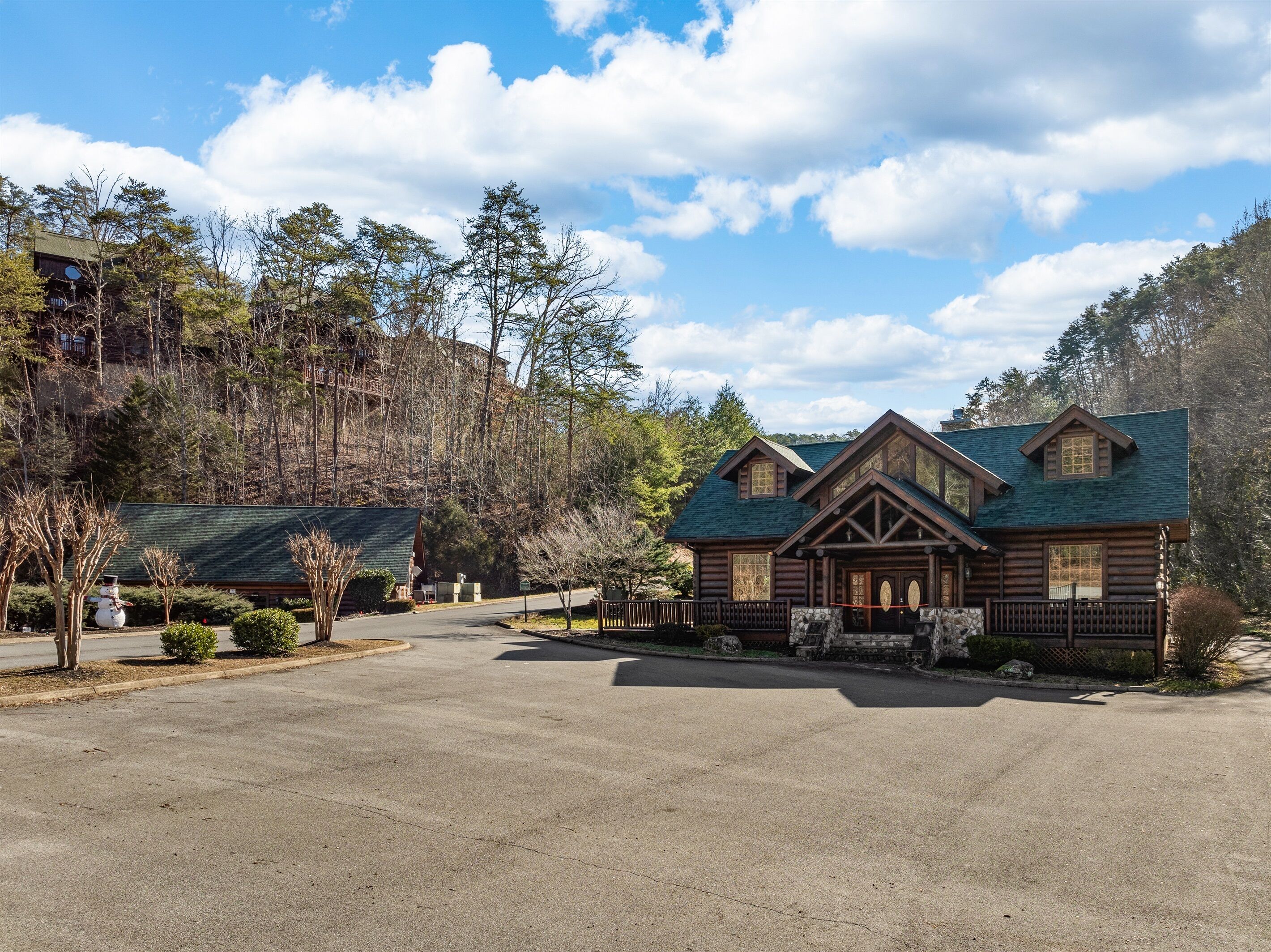 A log cabin with a green roof, surrounded by a stone wall and a wooden fence.