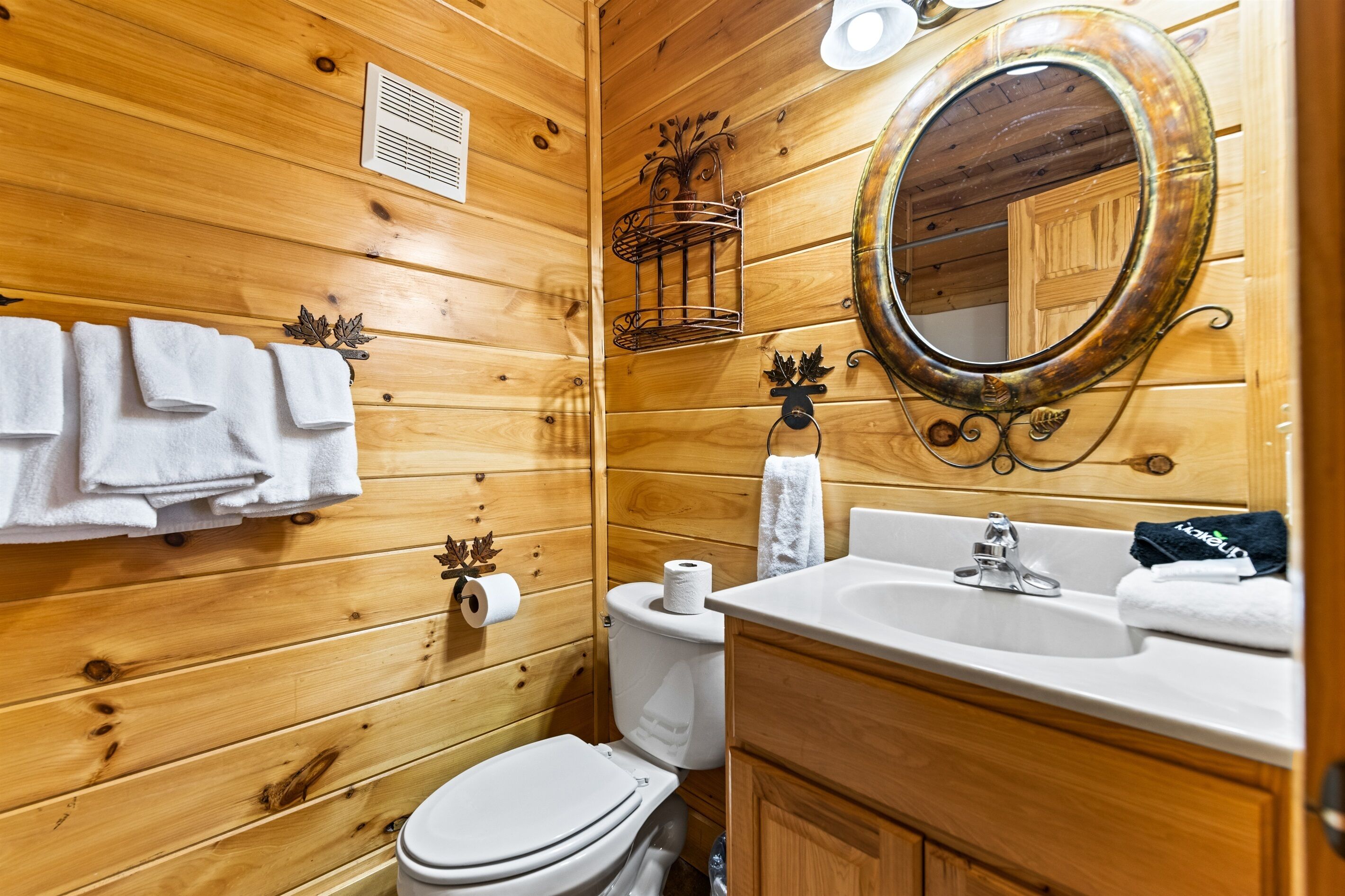 A wooden-paneled bathroom with a toilet, sink, and mirror.
