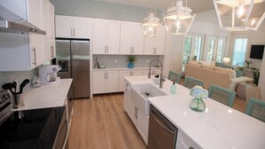 A modern kitchen with white cabinets, stainless steel appliances, and a central island. - 30A Fun in the Sun 5 minute walk to a Public Beach no Private Beach Hassles (Santa Rosa Beach)