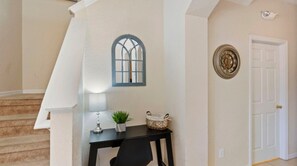 Uma escadaria que leva a um patamar com uma pequena mesa, um vaso de planta e um objeto decorativo na parede.