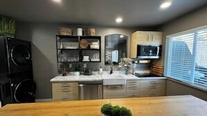 A modern kitchen with a wooden dining table, built-in appliances, and a large window. - Oasis in The City - Executive Retreat- Long Term Welcome (Grand Junction)