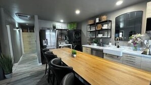 A modern kitchen with a wooden island, black chairs, and a built-in oven. - Oasis in The City - Executive Retreat- Long Term Welcome (Grand Junction)