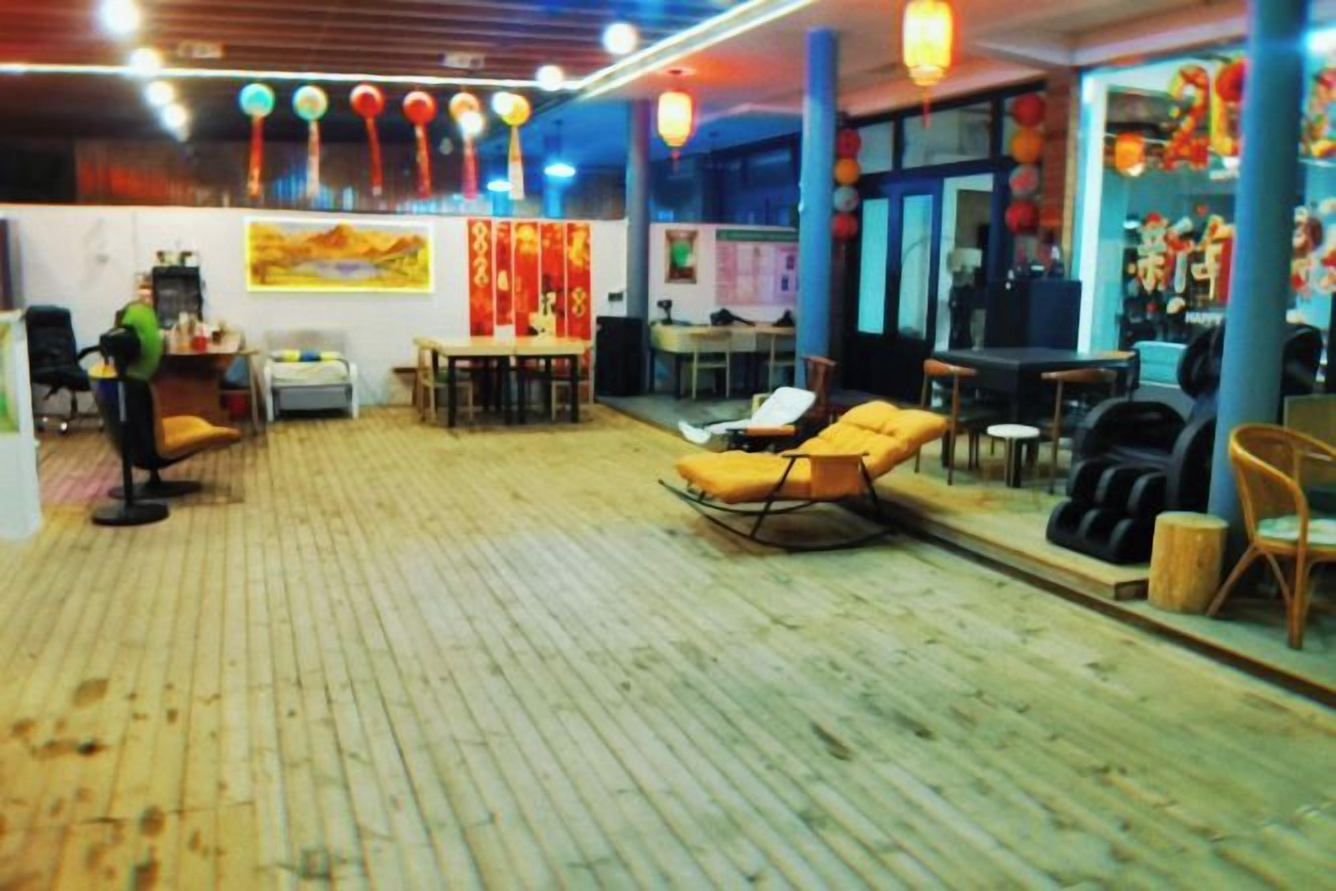 A room with a wooden floor, a sofa, a table, and a chair. There is a window and a door.