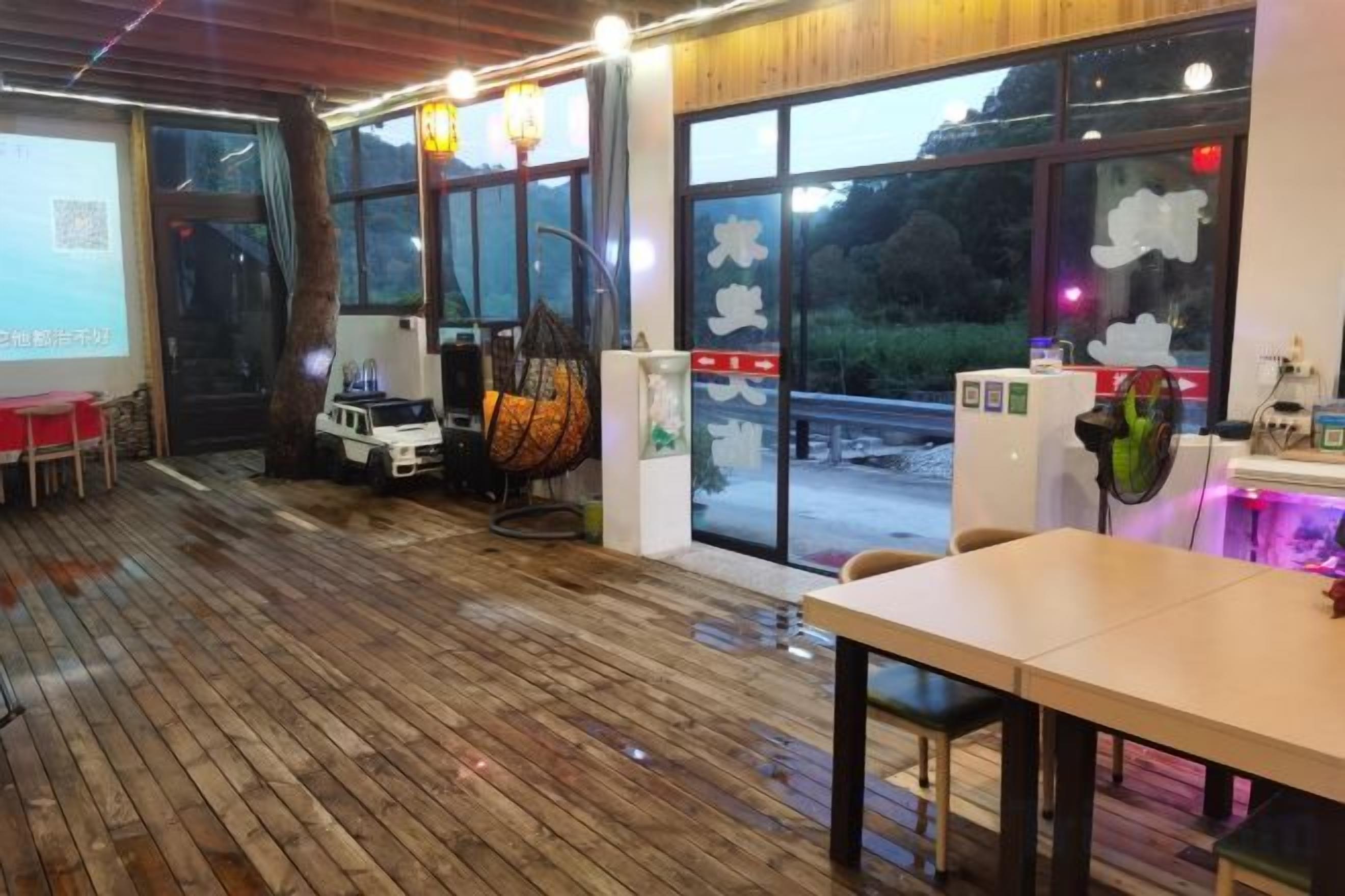 Un restaurant doté d’un plancher en bois, de grandes fenêtres et d’un espace où sont disposées des tables et des chaises.