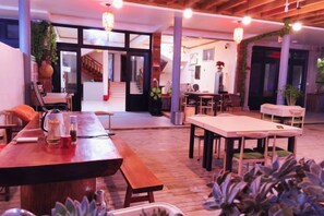 Un espace intérieur spacieux avec une table et des bancs en bois, un escalier en arrière-plan et des plantes en pot.