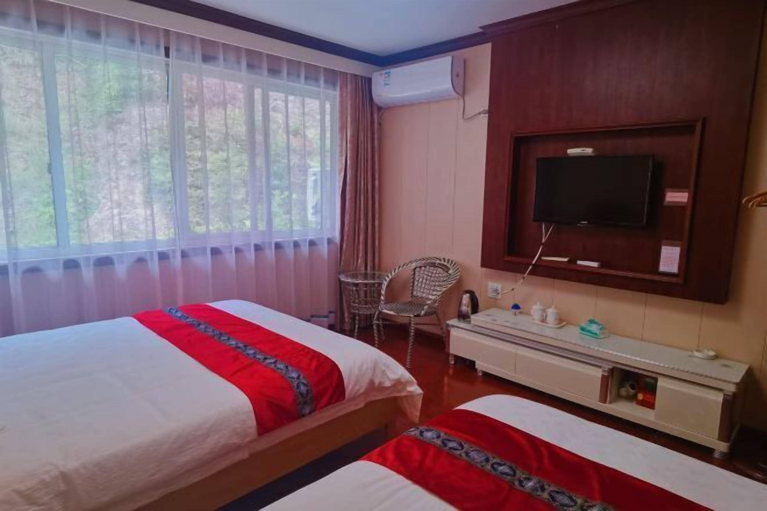 A hotel room with two beds, a TV, a small table, and a chair.