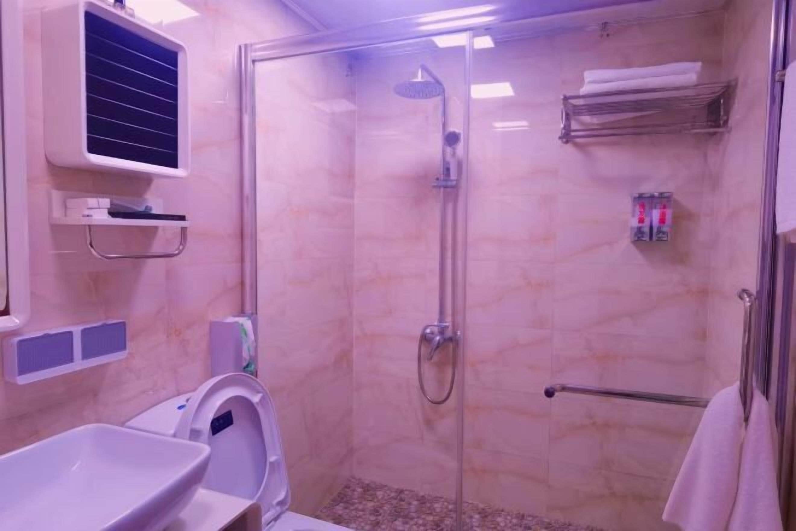 A bathroom with a glass-enclosed shower, a toilet, and a sink.