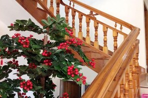 Una escalera con barandillas de madera y una planta en maceta con bayas rojas.