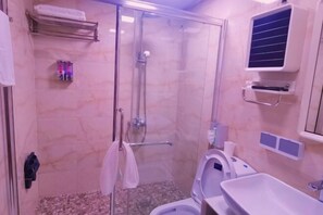 Een badkamer met een douche met glazen wand, een toilet, een wastafel en een handdoekhouder.