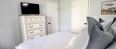Un dormitorio con cama, ventilador de techo, cómoda y televisor encima.