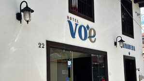 A hotel named 'Hotel Voé' with a number '22' on the facade, a glass entrance, and a sign indicating 'VISA' acceptance. - VOE HOTEL (San Cristóbal de las Casas)
