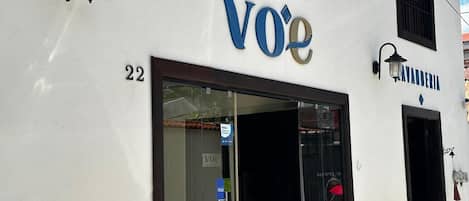 Un hotel llamado 'Hotel Voé' con el número '22' en la fachada, entrada de vidrio y un letrero que indica que acepta 'VISA'.