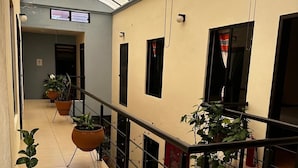 A corridor with potted plants, a metal railing, and a tiled floor. - VOE HOTEL (San Cristóbal de las Casas)