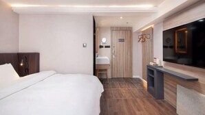 A modern hotel room with a large bed, a vanity with a mirror, a television, and a wooden door. - HanTing Premium Hotel (Shanghai Pudong Airport Chenyang Road) (Shanghai)