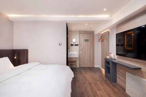 A modern hotel room with a large bed, a vanity with a mirror, a television, and a wooden door. - HanTing Premium Hotel (Shanghai Pudong Airport Chenyang Road) (Shanghai)