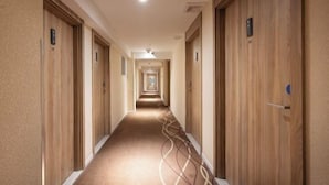 A hotel hallway with wooden doors, numbered room signs, and a carpeted floor. - HanTing Premium Hotel (Shanghai Pudong Airport Chenyang Road) (Shanghai)