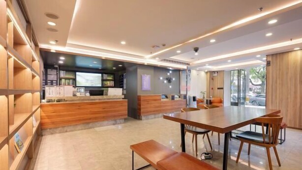 A modern hotel lobby with a reception desk, seating area, and a large window offering a view of the outdoors. - HanTing Premium Hotel (Shanghai Pudong Airport Chenyang Road) (Shanghai)
