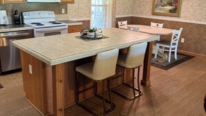 A kitchen with wooden cabinets, a white stove, a microwave, and a dining area with a table and chairs.