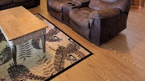 A living room with a brown leather sofa, a wooden coffee table, and a ceiling fan.