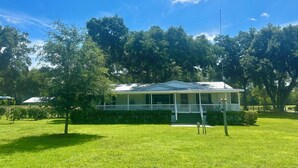A single-story house with a porch, surrounded by a well-maintained lawn and trees.
