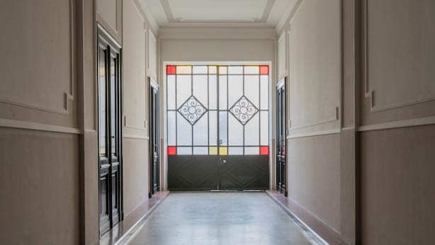 A hallway with a closed door featuring a decorative glass panel with geometric patterns and a black gate. - Appartamento Agnelli vicino al Pala Alpitour by Wonderful Italy (Turin)