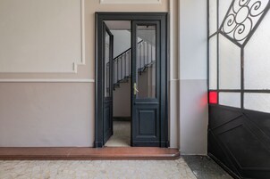 Un corridoio con una porta nera che dà su una scala.