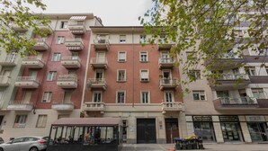 A multi-story residential building with balconies, a storefront, and a parked car. - Appartamento Agnelli vicino al Pala Alpitour by Wonderful Italy (Turin)