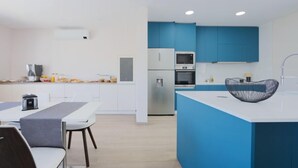 A modern kitchen with blue cabinets, a white countertop, and a black bowl on the island. - Refúgio da Garça (Chaves)