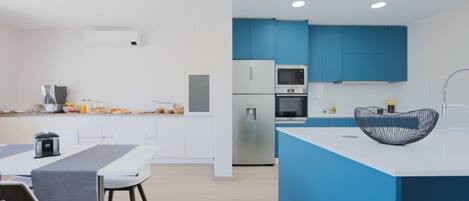 Una cocina moderna con armarios azules, una encimera blanca y un tazón negro en la isla.