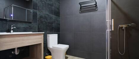 A modern bathroom with a toilet, sink, and shower.