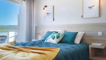 Habitación de hotel con una cama grande, vistas al exterior y dos cuadros en la pared.