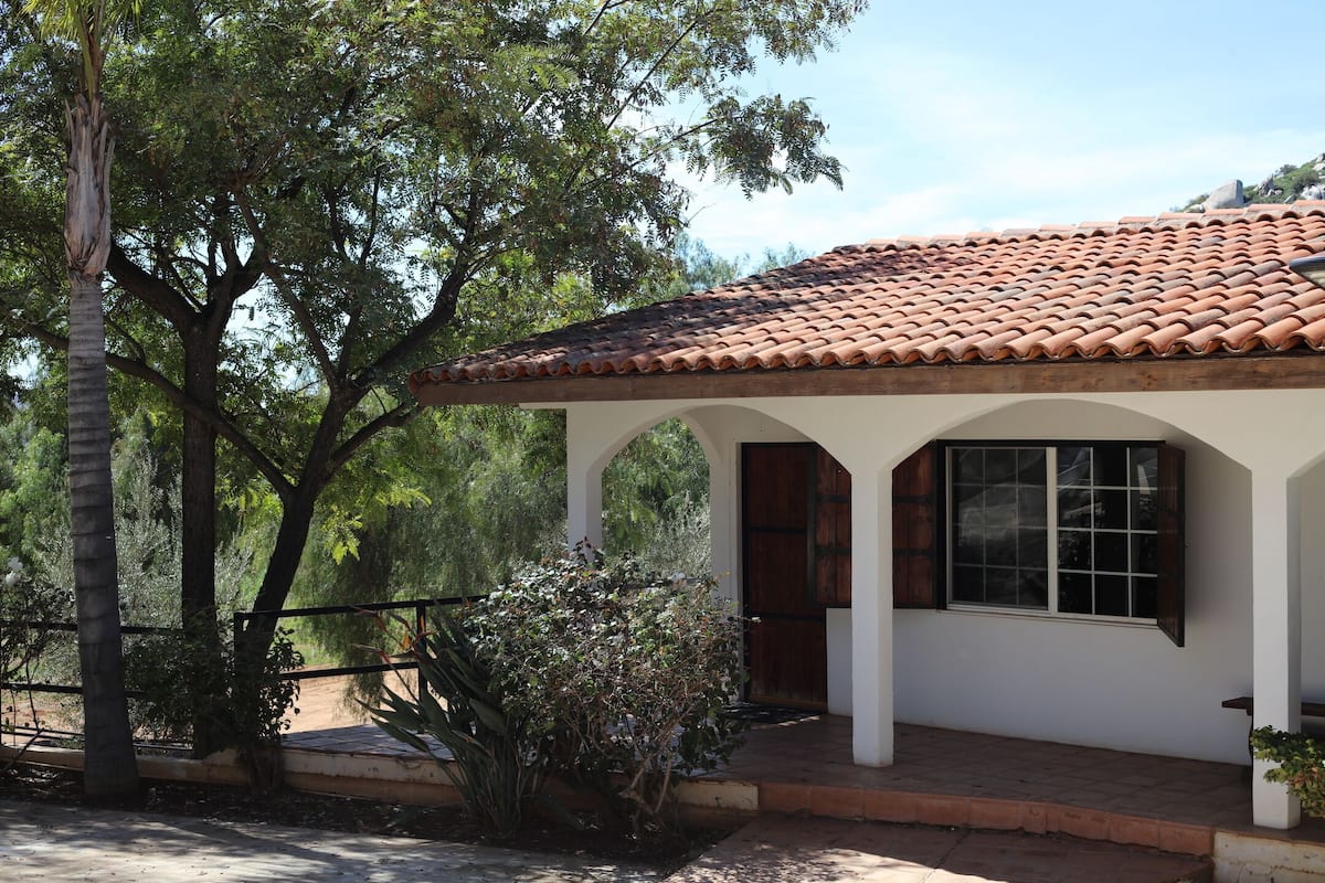 A house with a tiled roof, white walls, and a window with shutters.