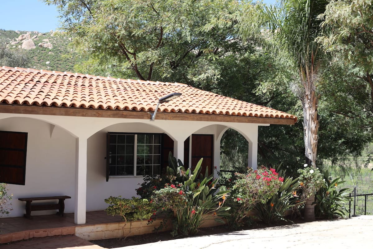 A building with a tiled roof, white walls, and a covered porch with a bench.