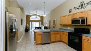 A spacious kitchen with wooden cabinets, stainless steel appliances, and a large island. - Beautiful 4 Bedroom Villa near Disney World with Private Pool (Kissimmee)
