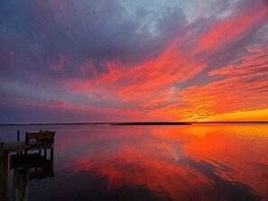 Ein Sonnenuntergang über ruhigem Wasser, mit einer anlegenden Mole.