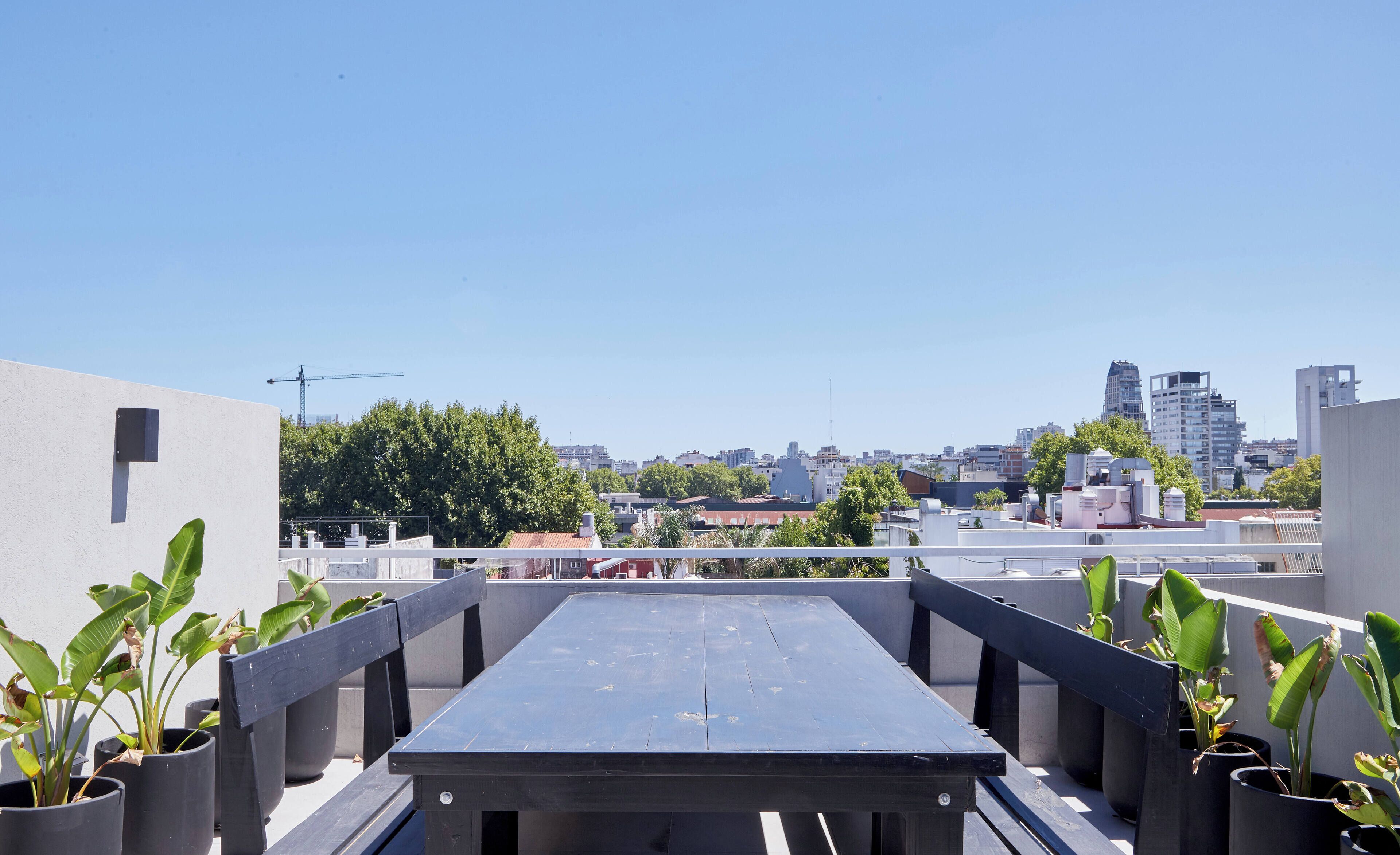 Een dakterras met uitzicht op een stadsgezicht, inclusief gebouwen en bomen.