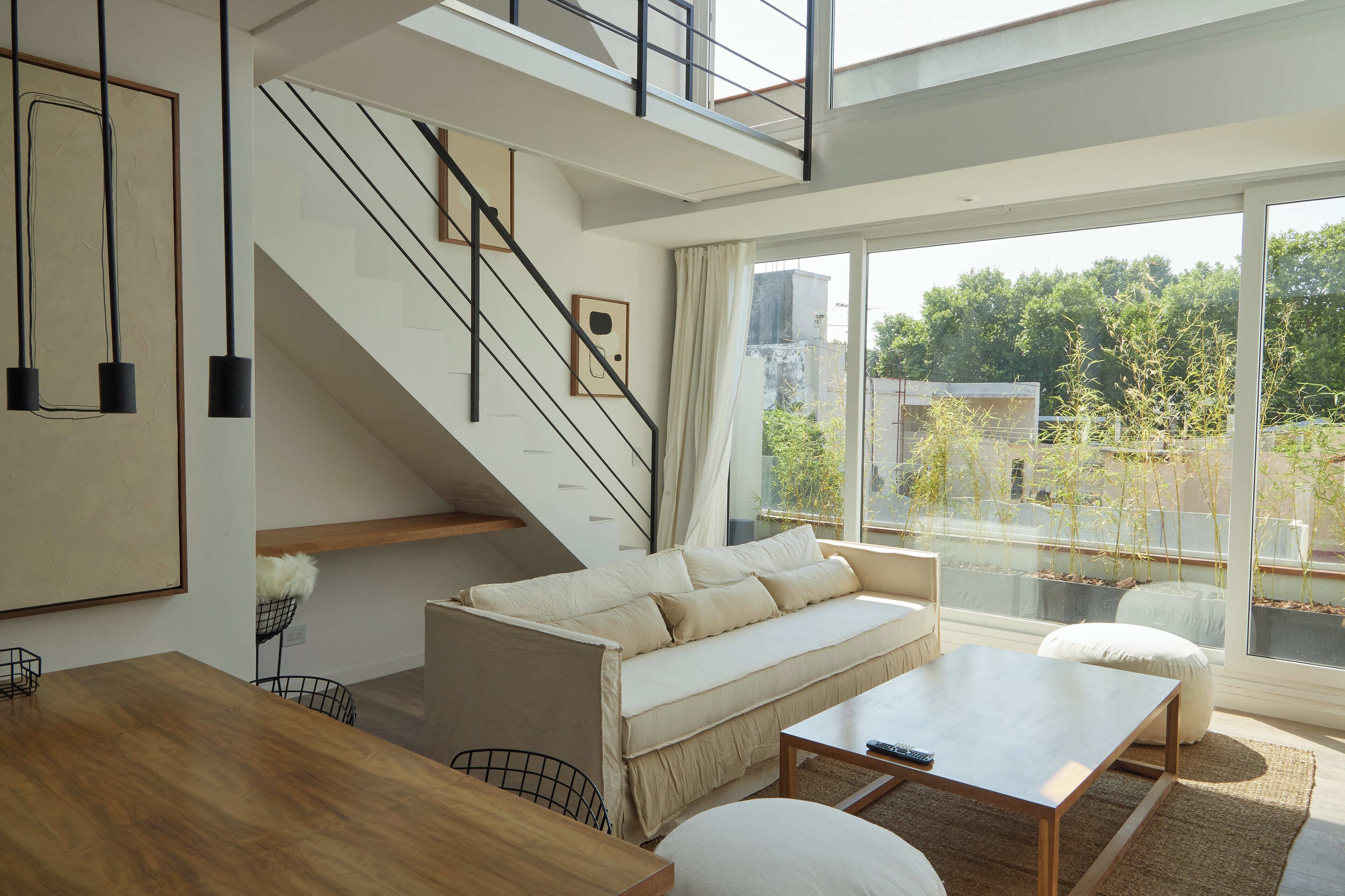 Una sala de estar moderna con un sofá, una mesa de centro y una escalera que conduce a un nivel superior.