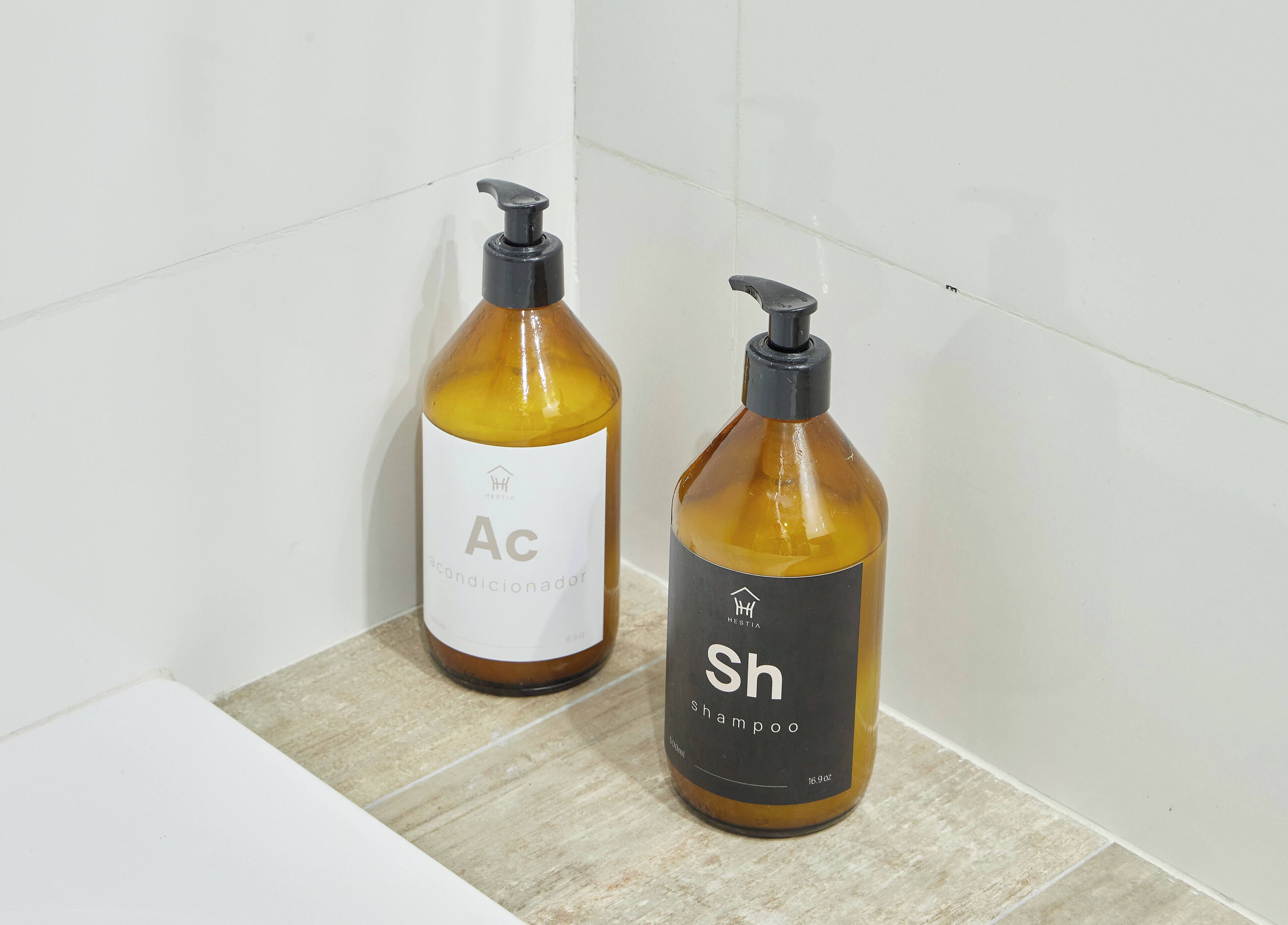 Dois frascos de shampoo e condicionador sobre uma superfície azulejada.