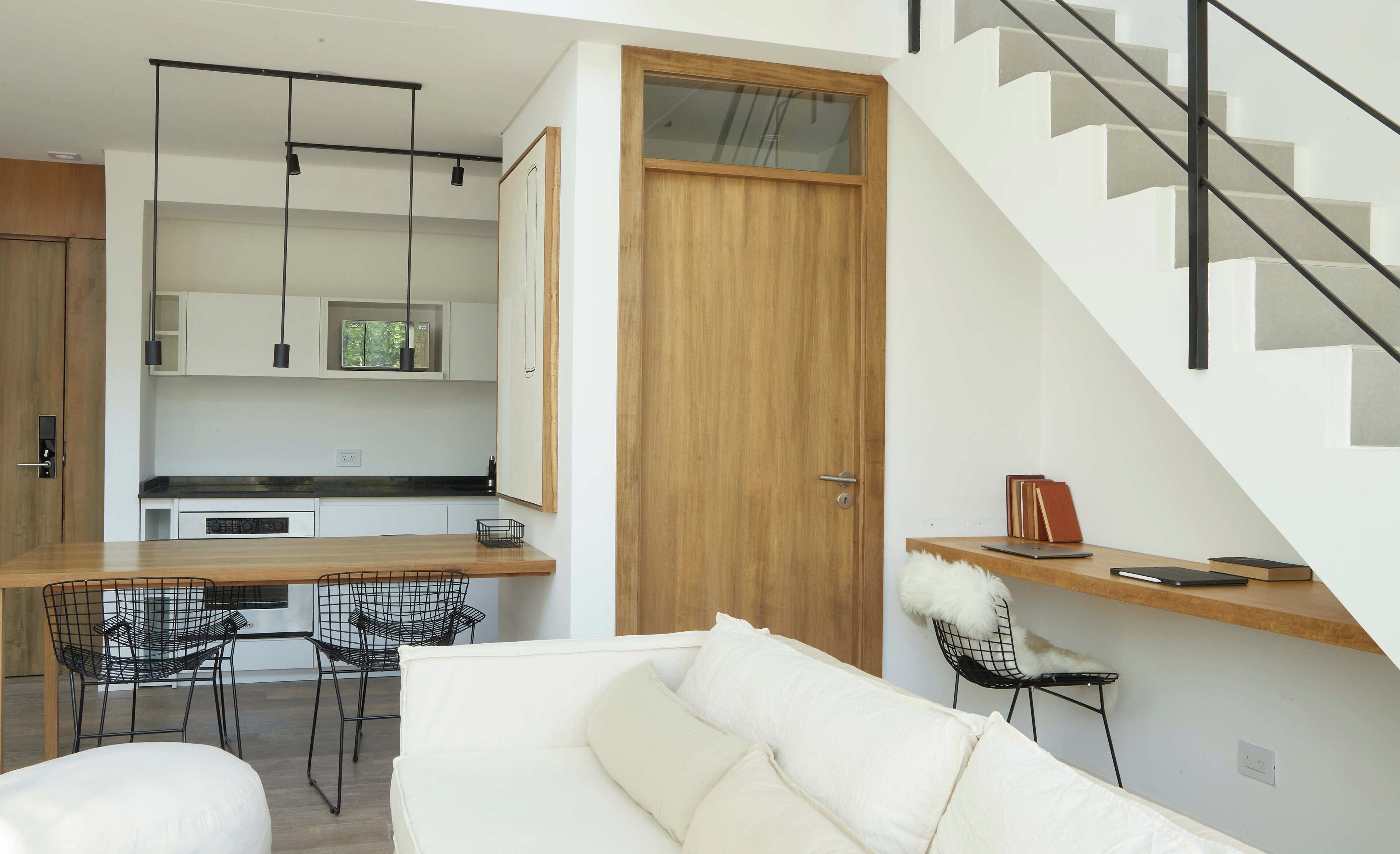 Una cocina moderna con encimera de madera, sillas negras y luces colgantes.