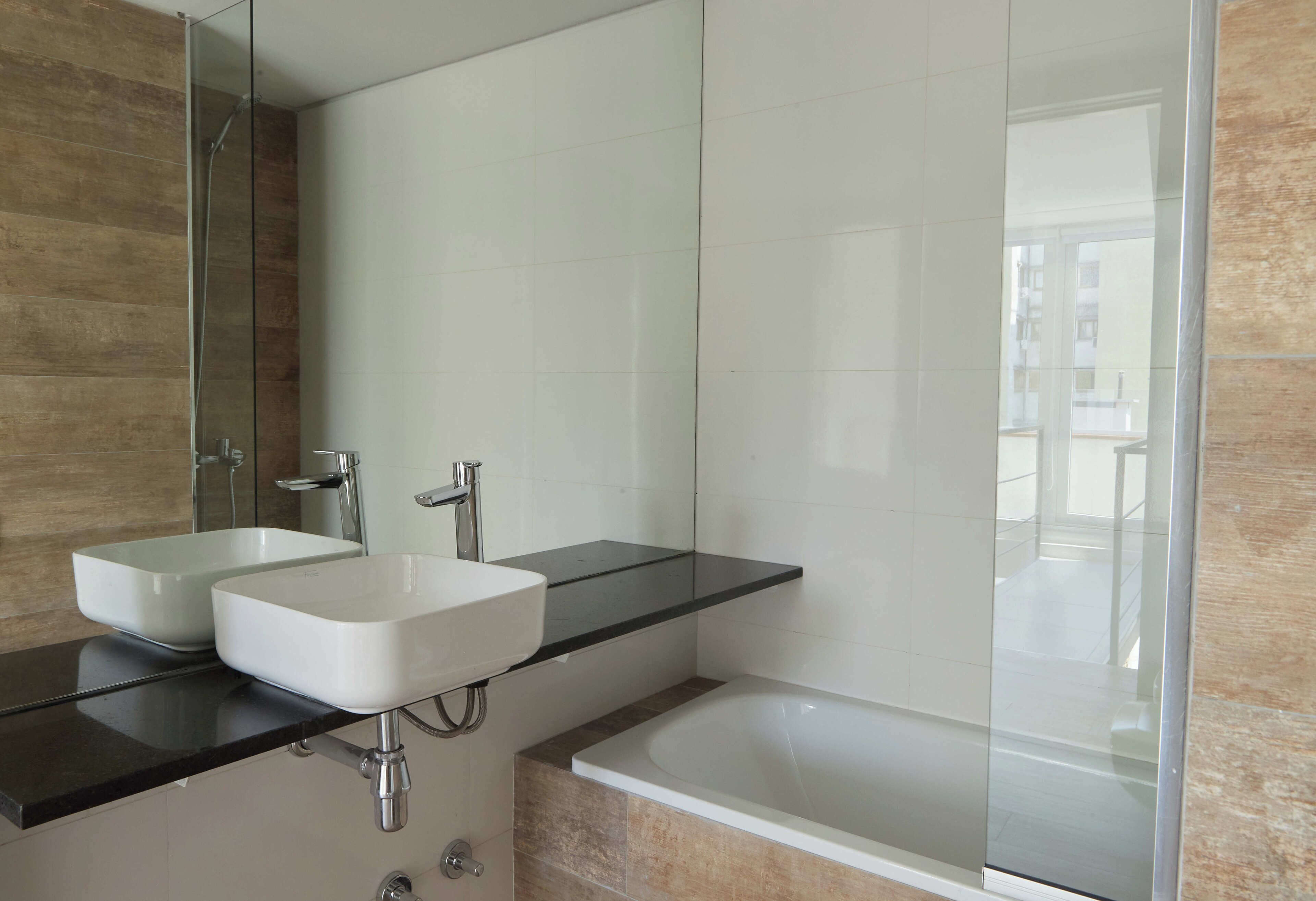 A modern bathroom with two sinks, a glass shower enclosure, and a bathtub.
