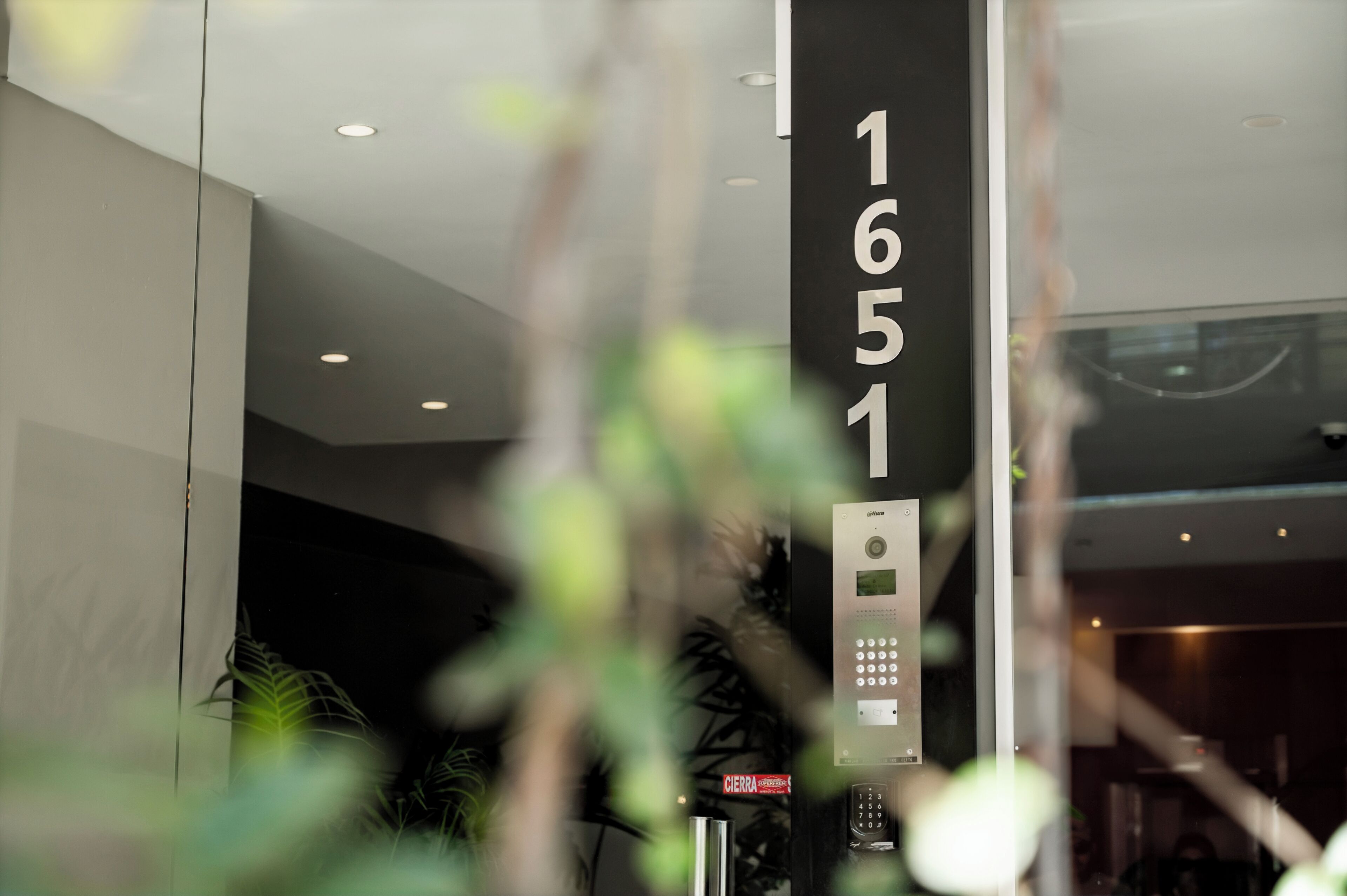 Entrada moderna de hotel con teclado digital y cartel que indica el número de habitación 1651.