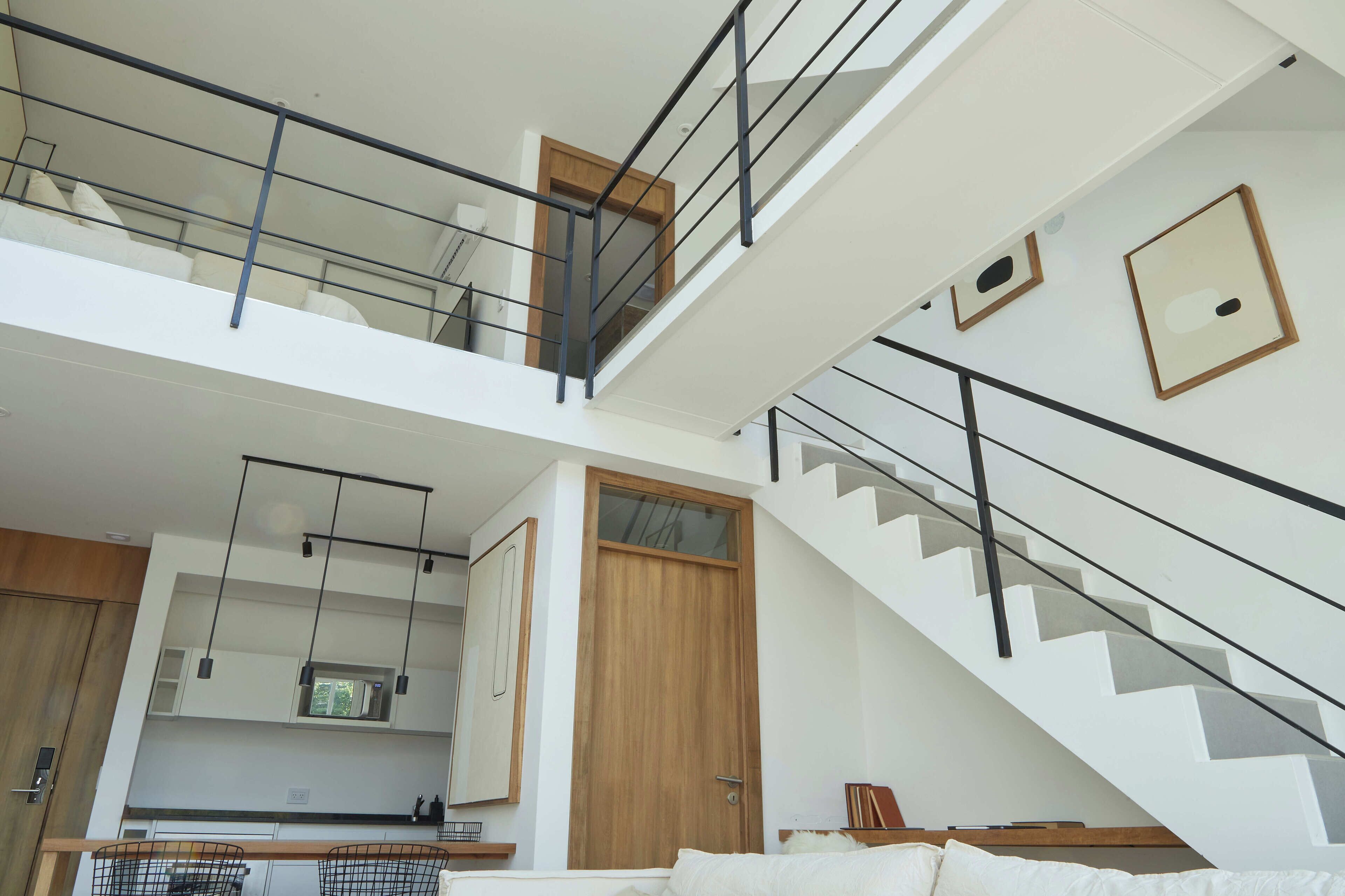 A modern apartment with a kitchen, a staircase, and a balcony.