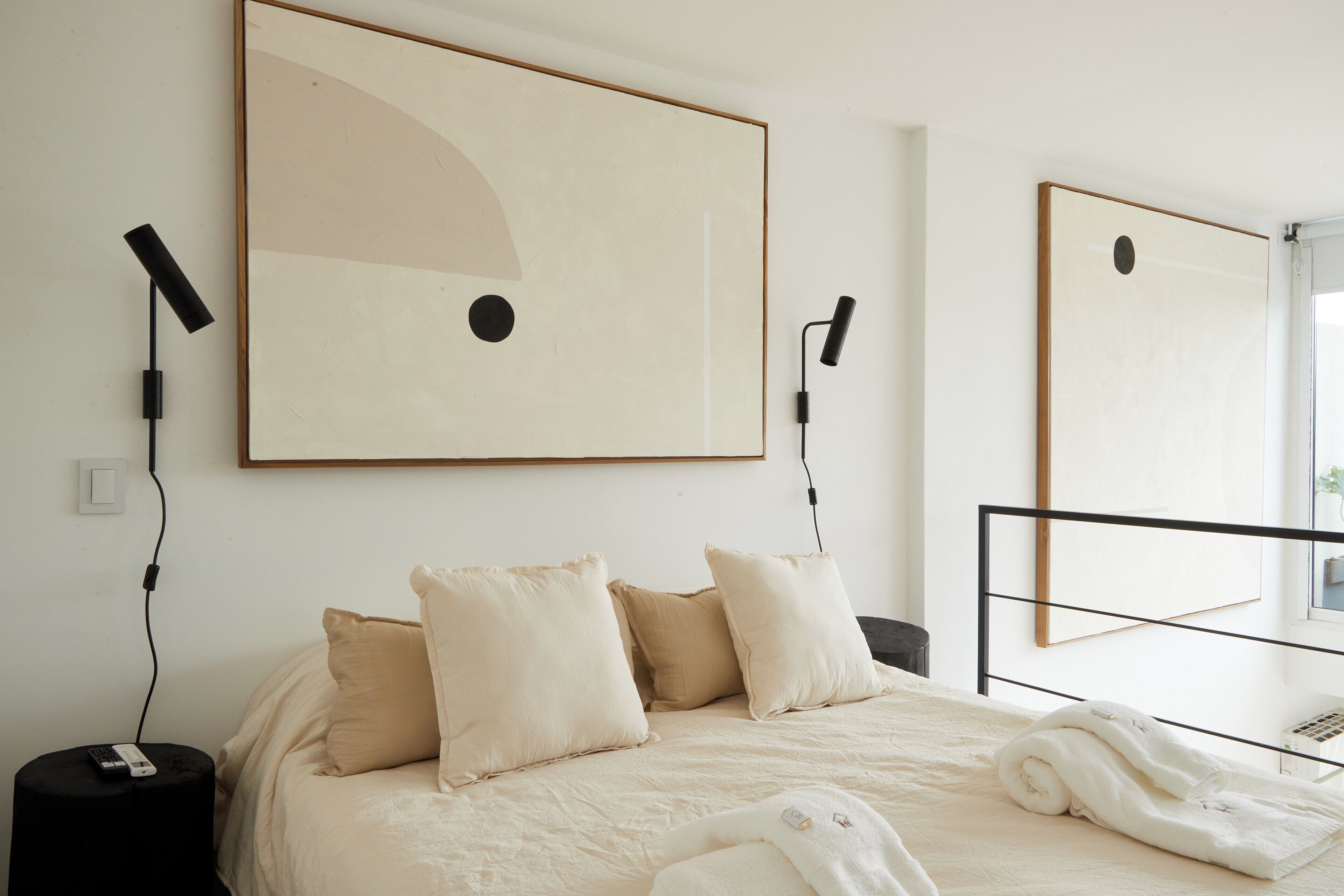 A bedroom with a bed, pillows, a blanket, and artwork on the wall.