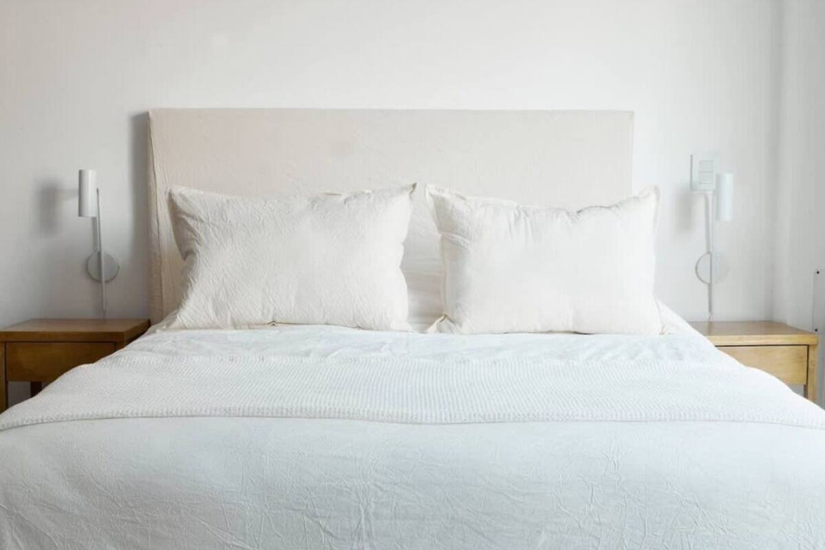 A neatly made bed with white bedding and two bedside lamps on wooden nightstands.