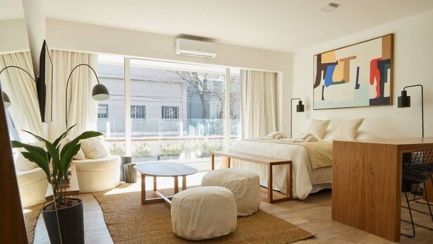 Ein modernes Schlafzimmer mit großem Fenster, einem Bett, einem Schreibtisch und einer Topfpflanze.