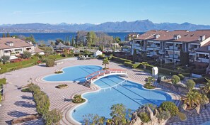 A resort with a large swimming pool, a bridge, and mountain views. - I Ciliegi 1-09 con Piscina by Wonderful Italy (Desenzano del Garda)